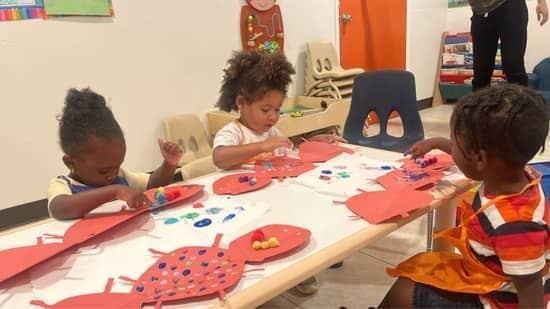 Toddlers at Christian childcare in Las Vegas creating colorful ladybug-themed crafts at a table.