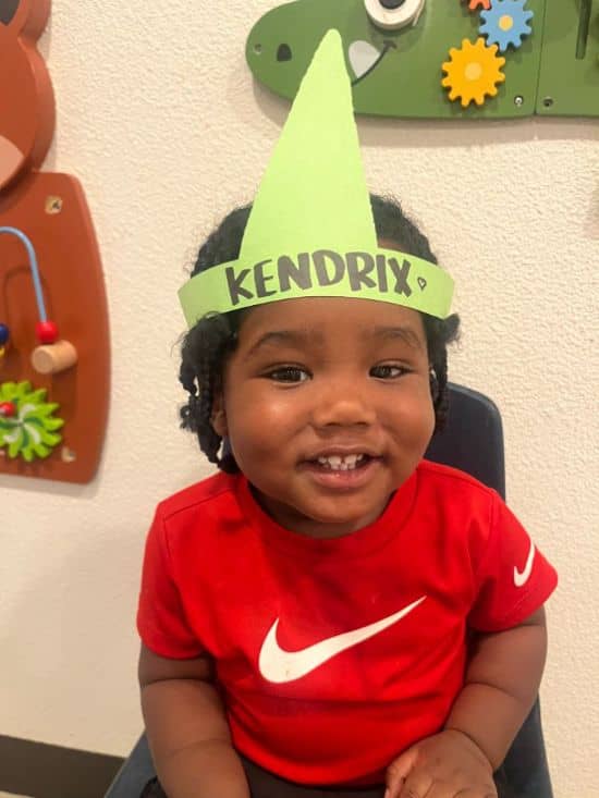 Smiling boy named Kendrix with a green handmade crown at a Christian daycare center in Las Vegas.